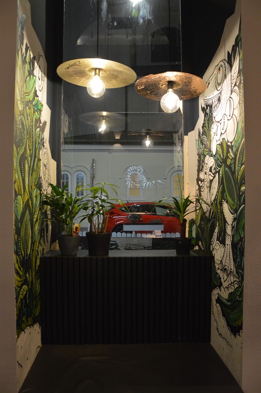The narrow entrance with plants and murals