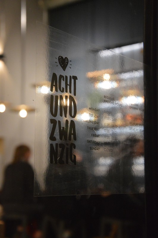 The achtundzwanzig logo on the glass door, guests behind