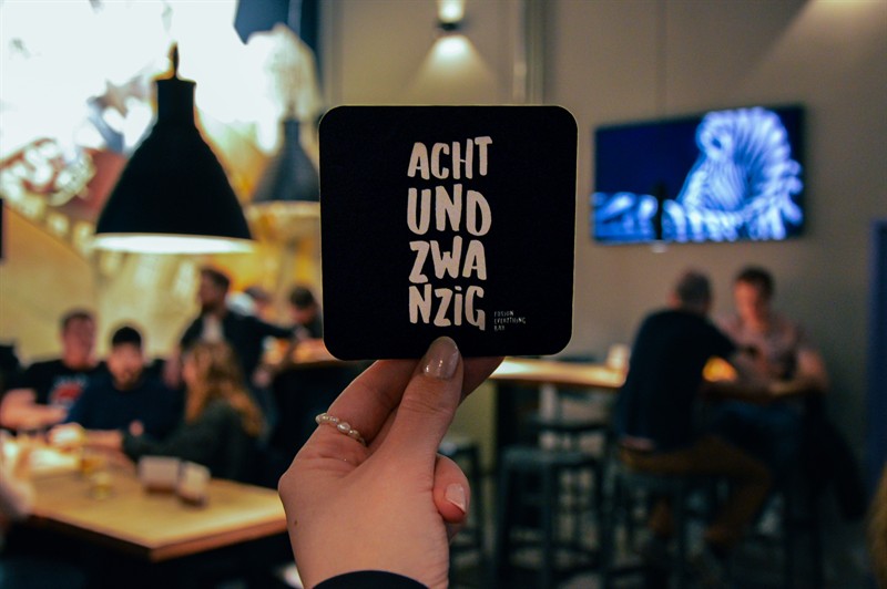 Holding up an achtundzwanzig coaster in a full room