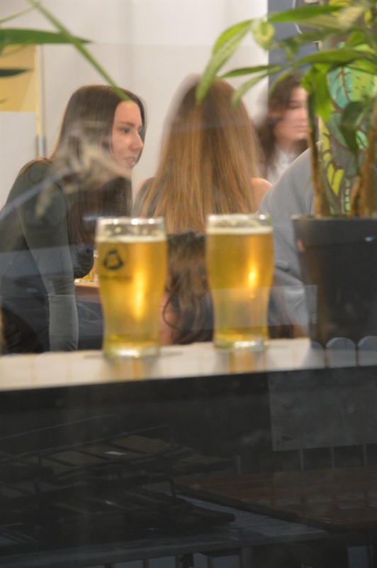 Two beers on the window ledge, friends chatting behind