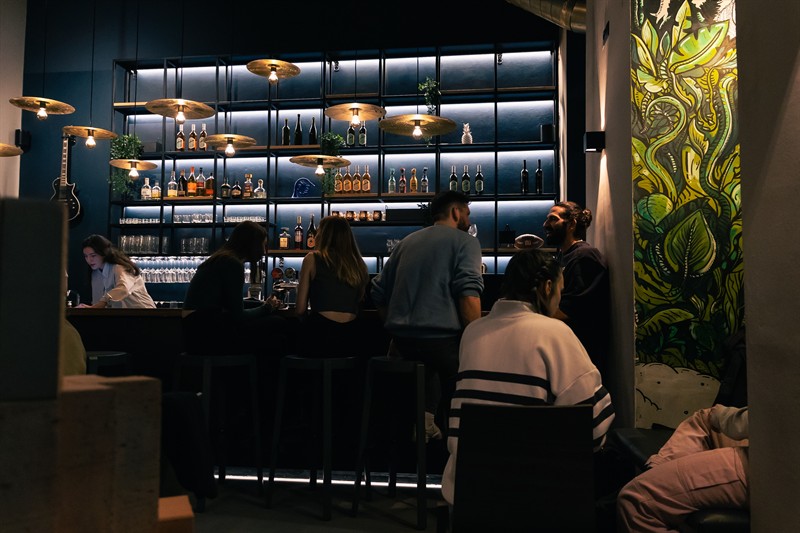 The bar at achtundzwanzig in Vienna's Josefstadt (1080): backlit shelves, brass cymbal lamps and the jungle mural
