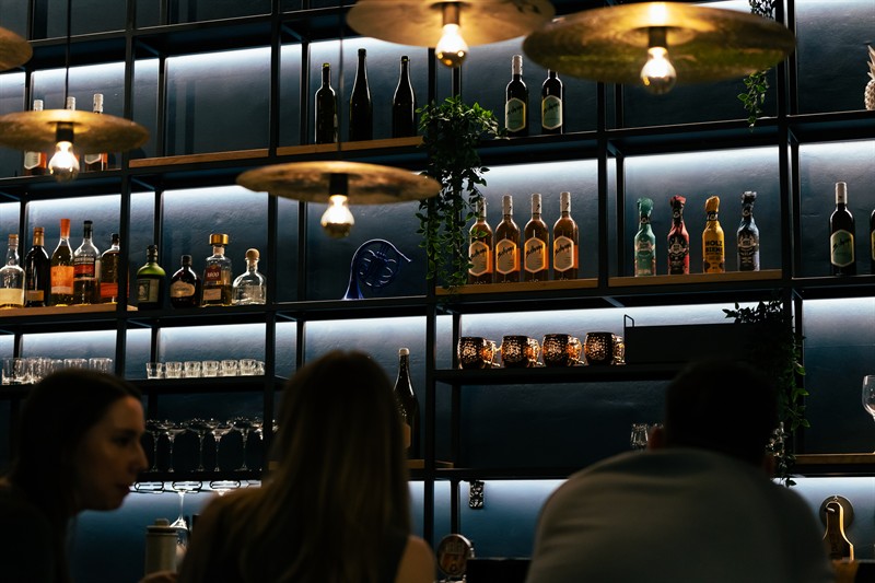 Guests at the bar under the cymbal lamps
